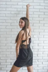 Vestido corto color fucsia con textura brillante, breteles finos y escote recto. Presenta corte tipo corsé con costuras fruncidas y falda ajustada.