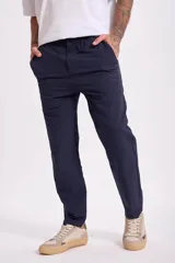 Pantalón de vestir azul marino, de corte recto, con bolsillos laterales y traseros. Se ajusta a la cintura con cinturón de cuero marrón.