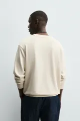 Sudadera color beige claro con cuello redondo y mangas largas.