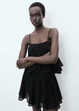 Vestido corto negro con tirantes finos, escote recto y falda con volados.