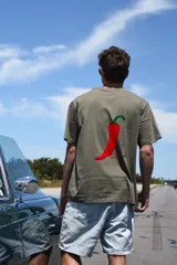Remera color beige de manga corta con estampado de un ají rojo.