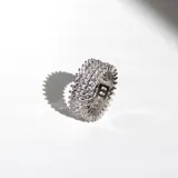 Anillo plateado decorado con cristales de diferentes tamaños, diseñado para destellar bajo la luz.