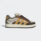 Championes Adidas Campus 00s color gris, con detalles en marrón y amarillo. Confeccionados en cuero con las tres tiras características de la marca en los laterales. Suela de goma color crema y cordones marrones.