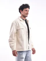 Campera gris oscuro de corte recto, con cuello clásico, cierre frontal con botones a presión, dos bolsillos de parche en el pecho con solapa y puños abotonados.