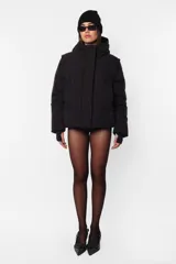 Campera puffer negra de corte oversize en textil impermeable. Con acceso delantero mediante cartera con abrojo y cierre oculto metálico desmontable. De cuello alto, con capucha forrada y tancas con elástico en su contorno interno. Bolsillos ribete en delantero con cierre oculto metálico. Mangas desmontables por cierre de nylon a tono con tela base, cubierto con vista. Terminación de manga con mitón, en textil de poliéster y elastano. Y en cintura, elástico por interior con tancas para regular su ajuste. Por su interior, forrería al tono. Cuenta con cinta gross estampado nombre de marca y snaps personalizados con logo en sus extremos, que permite transportarla al hombro. Bolsillo interno estampado con rapport de logo en lado izquierdo con cierre invisible.