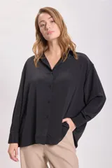 Camisa negra de manga larga con cuello clásico y cierre frontal con botones.