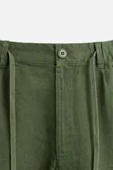 Bermuda negra regular fit confeccionada en tejido con mezcla de algodón y lino. Cintura elástica ajustable con cordón. Pliegues frontales. Bolsillos laterales y traseros de vivo. Cierre frontal con cremallera y botón.