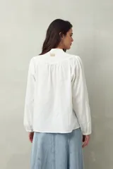 Camisa blanca de algodón con cuello mao, mangas abullonadas con puños abotonados y calados centrales.