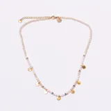 Gargantilla tipo choker compuesta por pequeñas cuentas facetadas de color blanco o crema, con pequeños dijes metálicos dorados en forma de moneda colgando a lo largo de la cadena. Posee un cierre de mosquetón y cadena de ajuste en tono dorado.