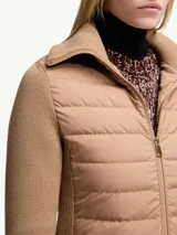 Cárdigan color beige con cierre frontal, mangas largas de punto acanalado y cuerpo acolchado con patrón horizontal.