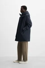 Parka azul marino de tejido técnico repelente al agua, corte regular fit, interior acolchado, cuello alto con capucha, mangas largas con puños de rib, cuello interior desmontable con cremallera, bolsillos de vivo en cadera y bolsillo interior. Cierre frontal con cremallera oculta por solapa con botones a presión.