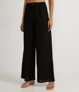 Pantalón wide leg negro de lino y viscosa, con cierre de botón y cremallera, trabillas y pliegues delanteros.