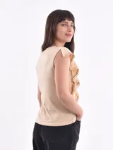 Remera blanca de cuello redondo con detalle de volados que nacen en los hombros y bajan por el frente.