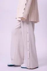 Pantalón de vestir color beige, de corte palazzo y tiro alto, con cierre lateral con botón y cremallera.