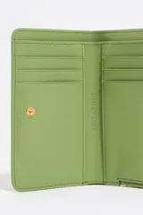Monedero pequeño con estampado animal print en tonos lila, negro y naranja. Tiene cierre con cremallera dorada y logo de la marca en el frente. Interior con tarjetero y forro con logo grabado.