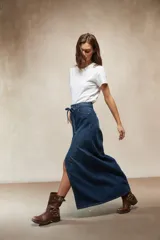 Falda larga de mezclilla color marrón chocolate, de tiro alto con cordón ajustable en la cintura y abertura frontal pronunciada.