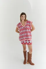 Chaleco tejido de lana con patrón de rombos en tonos lila, rojo y beige, con cuello en V y ribetes en color crema. Diseño oversize.