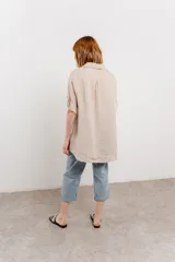 Camisa color beige de lino, con corte recto y calce suelto, cuello camisero, botones en el frente y mangas cortas con presilla y botón.