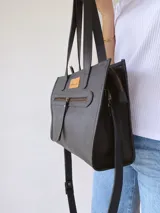 Cartera tipo tote bag de cuero color negro, con doble asa de mano y correa larga extraíble y regulable. Tiene un bolsillo frontal con cierre y un bolsillo interno.
