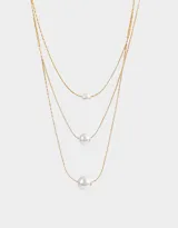 Collar corto de triple cadena dorada con perlas blancas de diferentes tamaños.
