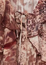 Blusa de gasa con estampado animal print en tonos marrones, cuello de pico con cierre de lazo, volantes en cuello y mangas largas acampanadas.