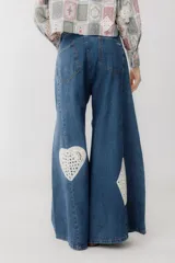 Pantalón de jean azul de corte wide leg con aplicaciones de crochet en forma de corazón, trébol, diamante y pica.