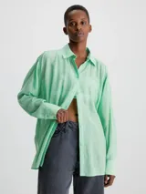 Camisa verde menta de rayón arrugado, corte regular, cuello en punta, manga larga con puños abotonados y espalda dividida con detalle anudado.