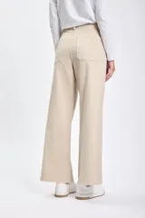 Pantalón jean de corte ancho color beige, con cintura alta y terminación desflecada.