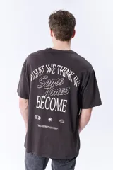 Remera gris oscuro de corte amplio con estampado circular en el pecho que dice 'What we think about we become'.