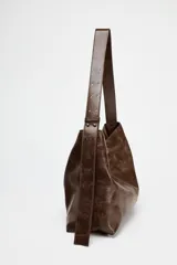 Bolso shopper marrón de efecto acharolado con asa de hombro ajustable, bolsillo interior con cremallera y cierre magnético.