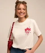 Remera blanca de algodón con cuello redondo y mangas cortas. Estampa pequeña "HSM Social Club" en el pecho y estampa grande "We Are All In This Together" en la espalda.