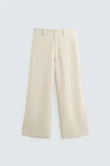 Pantalón de pana color beige, corte wide fit, con bolsillos frontales y traseros de vivo. Cierre frontal con cremallera y botón.