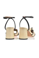 Sandalia de tacón mediano color beige con detalle negro, de diseño elegante y cierre en el tobillo.