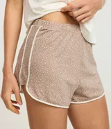 Conjunto de pijama compuesto por una remera de manga corta color blanco hueso con un estampado central de un cervatillo y una mariposa, y un short de tiro bajo color marrón topo con estampado de mini puntos blancos y ribetes blancos en los bordes.