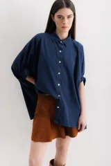 Camisa azul de mangas cortas abullonadas, con cuello clásico y cierre frontal con botones.