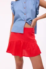Falda corta de lino color rojo, con diseño de tiro alto y un volado en el ruedo. Posee cierre en la parte posterior.