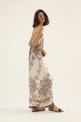 Mono largo de tirantes finos con estampado floral en tonos marrones sobre fondo blanco.