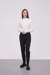 Pantalón negro a rayas verticales blancas, de corte skinny.