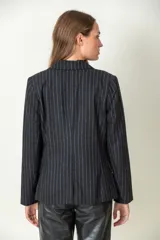 Blazer negro con finas rayas verticales blancas, solapas clásicas y cierre con dos botones.