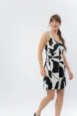 Vestido corto con breteles anchos y escote en “V”, confeccionado en lino metalizado, con abotonadura frontal y corte entallado en el busto que se abre levemente hacia el ruedo.
