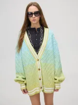 Cardigan tejido de punto con patrón de rombos en degradé de grises y blanco. Tiene corte oversize, mangas largas y cierre frontal con botones.