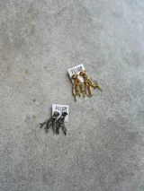 Aros colgantes dorados con forma de ramitas irregulares. Hechos a mano en bronce y porcelana con mix de piedras y materiales para darle textura.