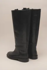 Bota alta de cuero color marrón, con caña recta y suela plana.