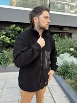 Campera de hombre color crema, de textura peluda, con cierre frontal, cuello alto, bolsillos laterales y un bolsillo impermeable negro en el pecho.