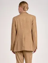 Blazer negro de gamuza con cuello solapado, cierre frontal con un solo botón forrado y bolsillos de parche en la parte delantera. Presenta un tajo vertical en la espalda.