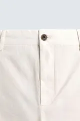 Pantalón chino negro de corte relajado (relaxed fit) con tiro medio, confeccionado en algodón con elasticidad. Presenta bolsillos delanteros y bolsillos traseros de vivo, con cierre frontal de cremallera y botón.