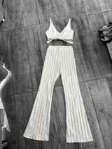 Conjunto de top y pantalón oxford a rayas verticales color blanco y marrón. El top es tipo corpiño con tirantes finos y lazo en la espalda. El pantalón es de tiro alto y corte acampanado.