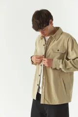 Sobrecamisa color beige de pana con cuello camisero, cierre frontal con botones, dos bolsillos de parche con botón en el pecho y bolsillos laterales.