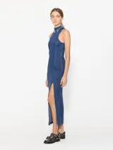 Vestido largo de denim azul con tajo lateral, sin mangas y cuello alto, con cierre en la espalda.