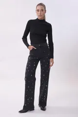 Pantalón de jean negro de corte recto, con detalle de ojalillos metálicos plateados en ambas piernas.